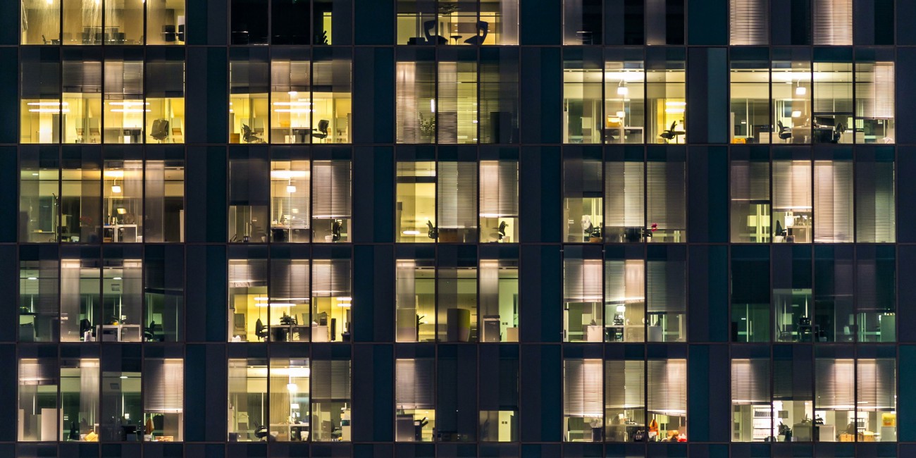 External shot of an office building at night with office lights visible.