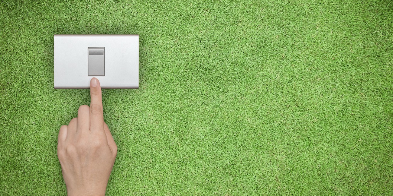 hand turning off switch that sits upon a green grass lawn