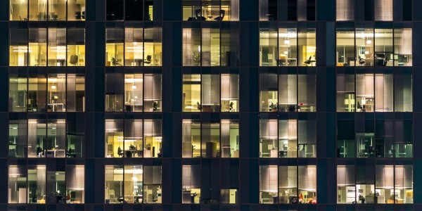 External shot of an office building at night with office lights visible.
