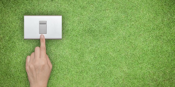 hand turning off switch that sits upon a green grass lawn