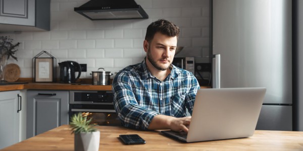 Man working on a laptop at kitchen table